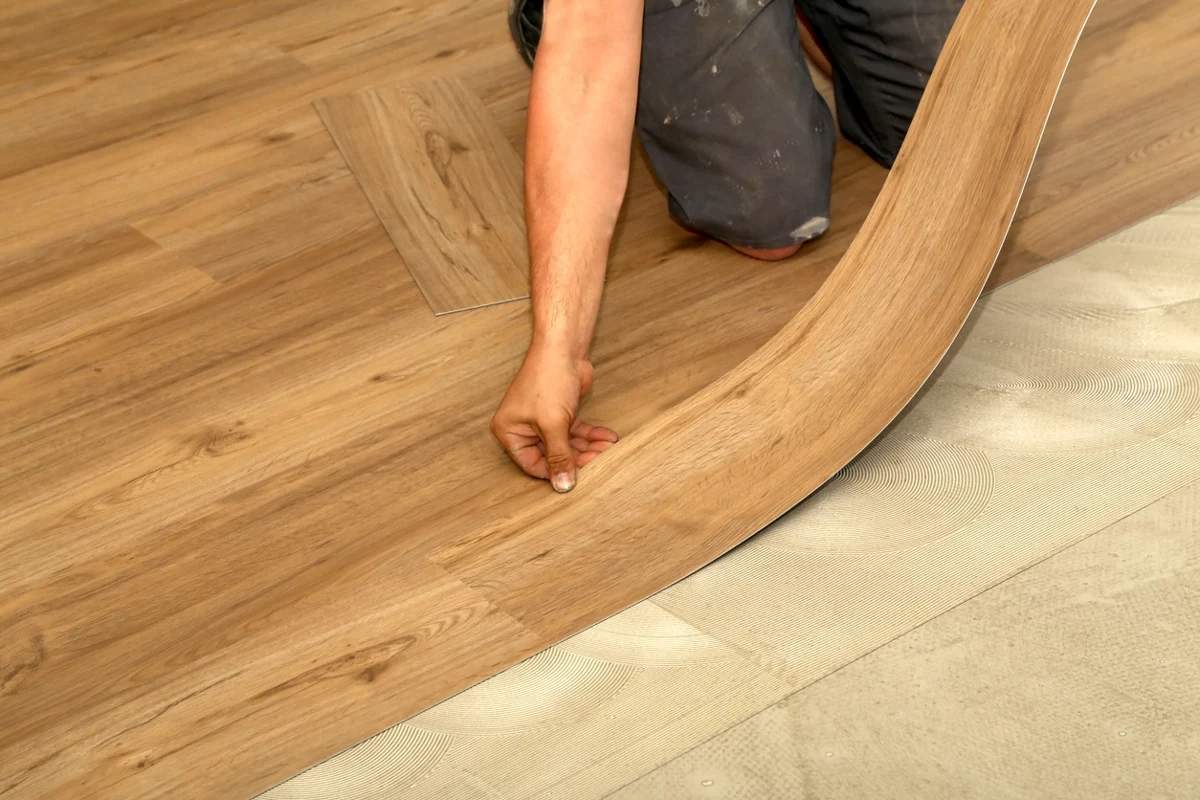 A fitter laying wood-effect sheet vinyl onto adhesive